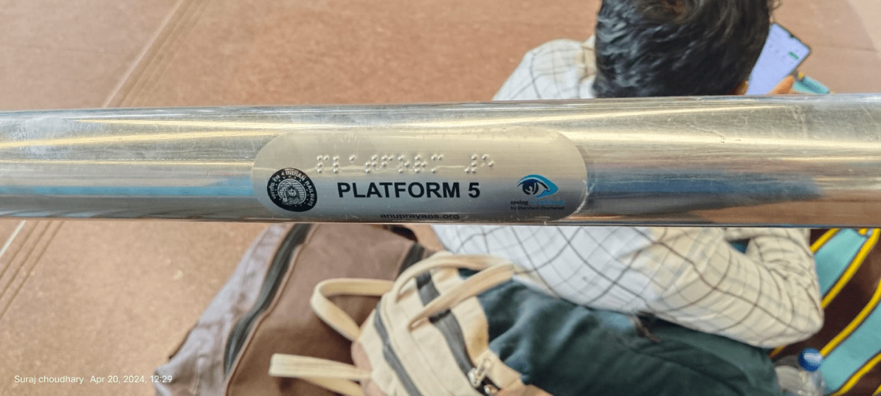 A metal rail at a railway station with a Braille and printed label reading 'Platform 5', indicating accessibility features for visually impaired travellers.