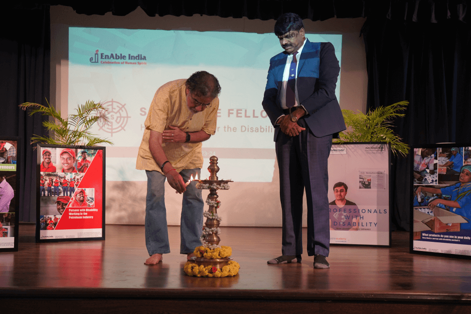 Fellow lighting ceremonial lamp on stage during Soapstone Fellowship inauguration