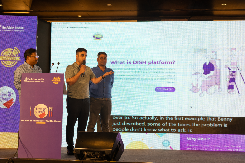 Three men on stage at the Launch of DISH and INCLUZZA Circle event, speaking in front of a screen showing the DISH platform.